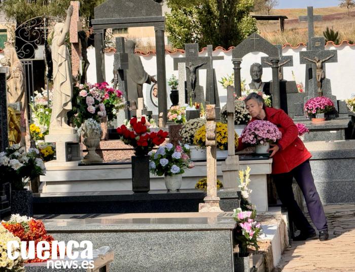 Una mujer porta un centro de flores en el Cementerio de Villar de Olalla