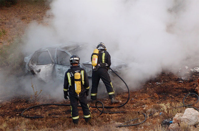 Los bomberos del  Cuenca 112 sofocan el incendio originado por el accidente de un coche en una zona arbolada